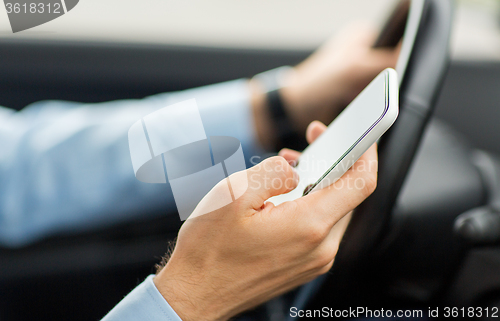 Image of close up of man hand with smartphone driving car