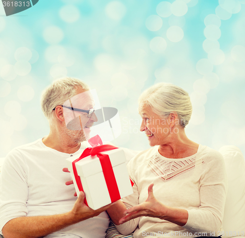 Image of happy senior couple with gift box at home