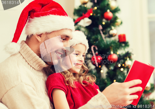 Image of smiling father and daughter reading book