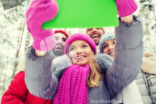 Image of smiling friends with tablet pc in winter forest