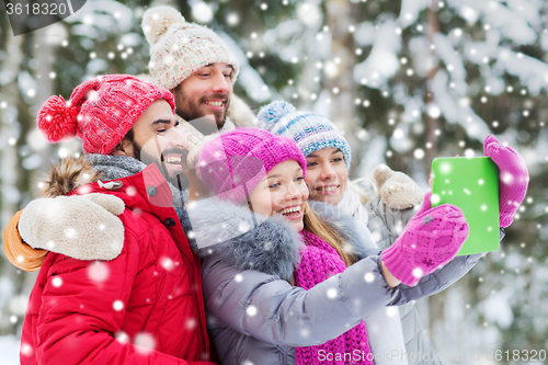 Image of smiling friends with tablet pc in winter forest