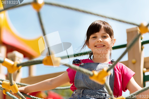 Image of happy little girl climbing on children playground