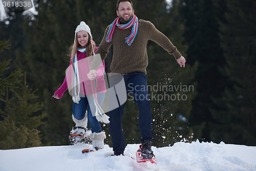 Image of couple having fun and walking in snow shoes