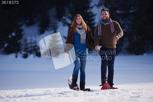 Image of couple having fun and walking in snow shoes