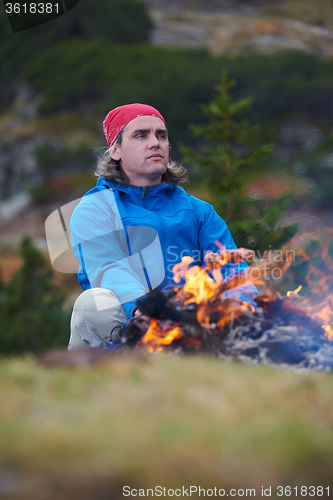 Image of hiking man prepare tasty sausages on campfire