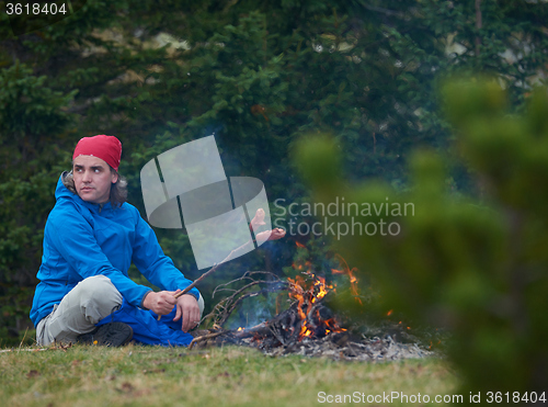 Image of hiking man prepare tasty sausages on campfire