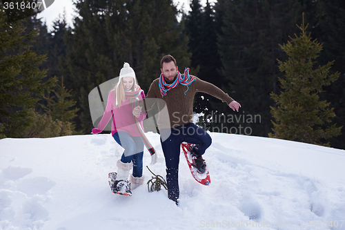 Image of couple having fun and walking in snow shoes