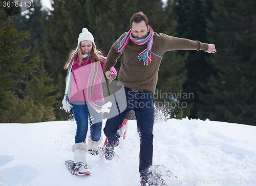 Image of couple having fun and walking in snow shoes