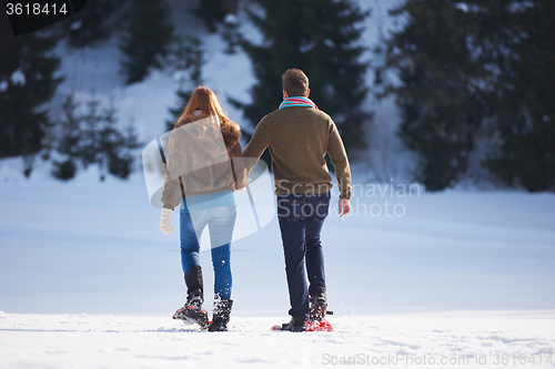 Image of couple having fun and walking in snow shoes