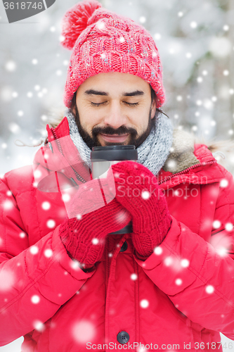 Image of smiling young man with cup in winter forest