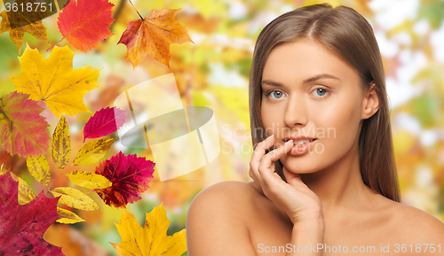 Image of beautiful young woman face over autumn leaves