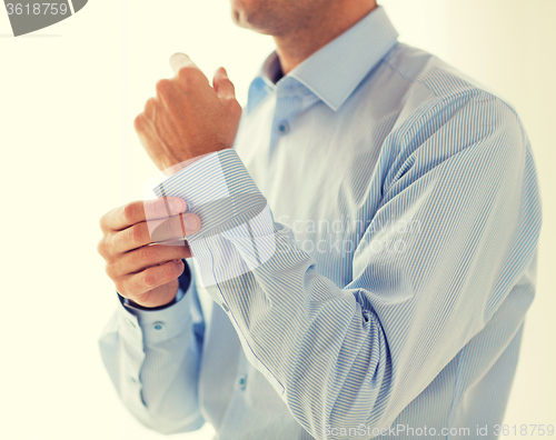 Image of close up of man fastening buttons on shirt sleeve