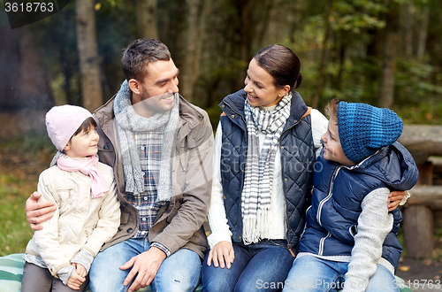 Image of happy family sitting on bench and talking at camp