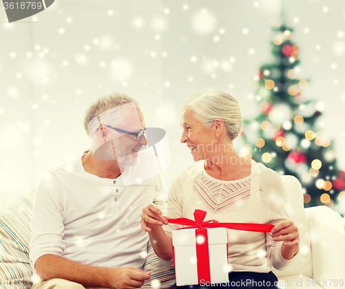 Image of happy senior couple with gift box at home