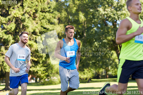 Image of happy young sportsmen racing wit badge numbers