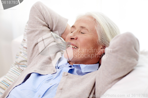 Image of happy senior woman resting on sofa at home