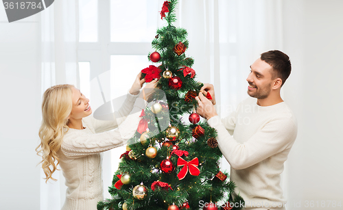 Image of happy couple decorating christmas tree at home
