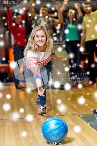 Image of happy young woman throwing ball in bowling club