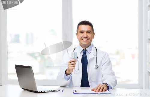 Image of smiling doctor with tablets and laptop in office