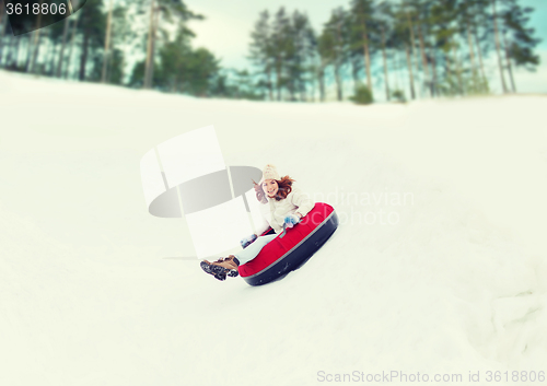 Image of happy teenage girl sliding down on snow tube