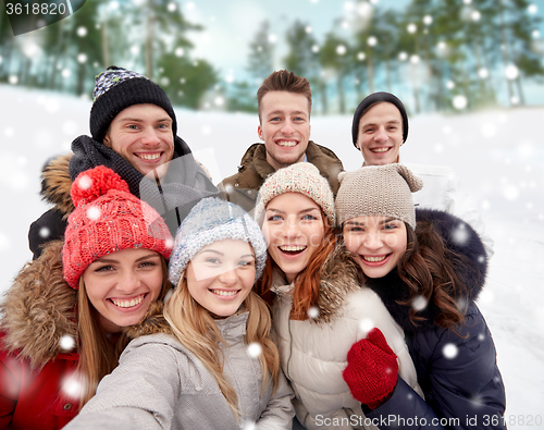 Image of group of smiling friends taking selfie outdoors