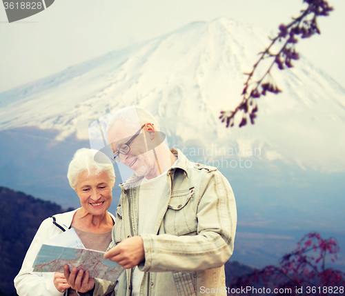 Image of happy senior couple with travel map over mountains