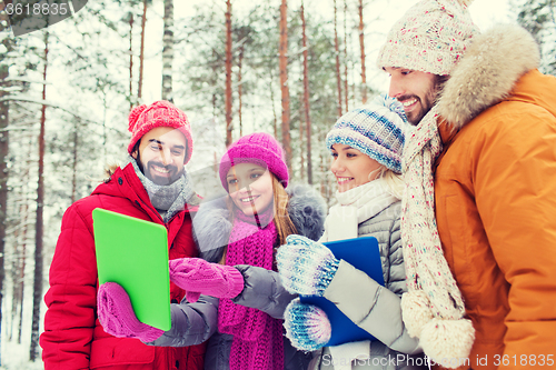 Image of smiling friends with tablet pc in winter forest