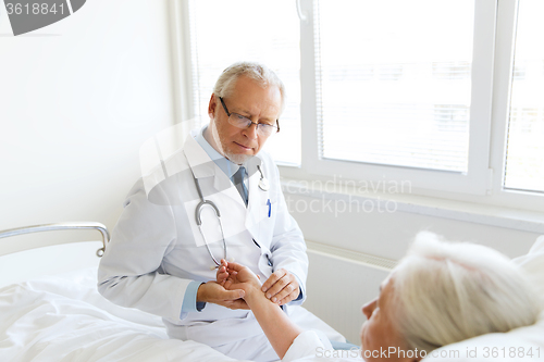 Image of doctor checking senior woman pulse at hospital