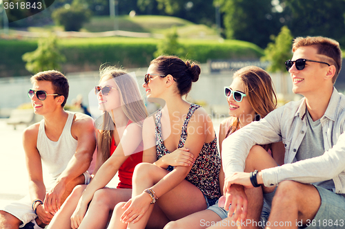 Image of group of smiling friends sitting on city square