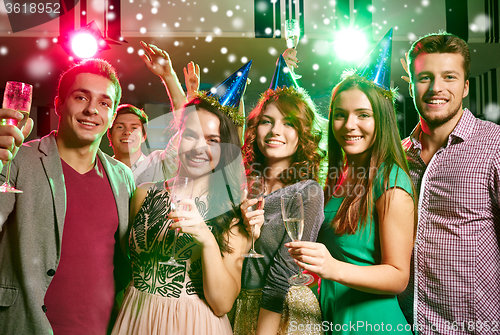 Image of smiling friends with glasses of champagne in club