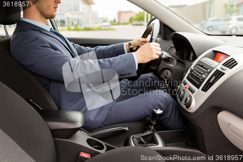 Image of close up of young man in suit driving car