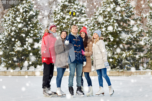 Image of happy friends with smartphone on ice skating rink