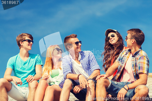 Image of group of smiling friends sitting on city street