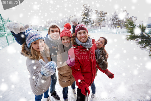 Image of happy friends with smartphone on ice skating rink