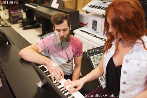 Image of man and woman playing piano at music store