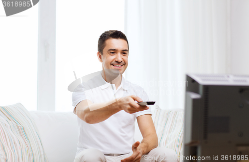 Image of smiling man with remote control watching tv