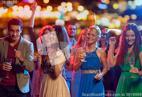 Image of happy friends with champagne dancing at nightclub