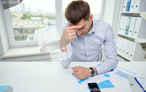 Image of stressed businessman with papers in office