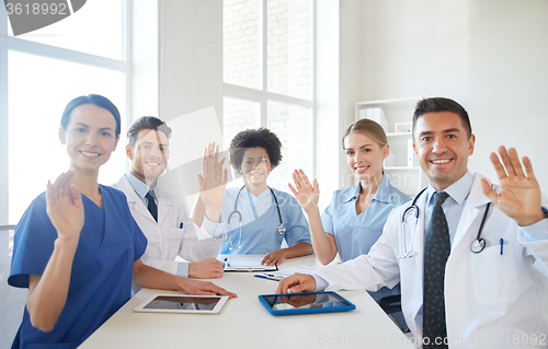 Image of happy doctors meeting and waving hands at hospital