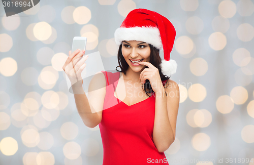 Image of woman in santa hat taking selfie by smartphone