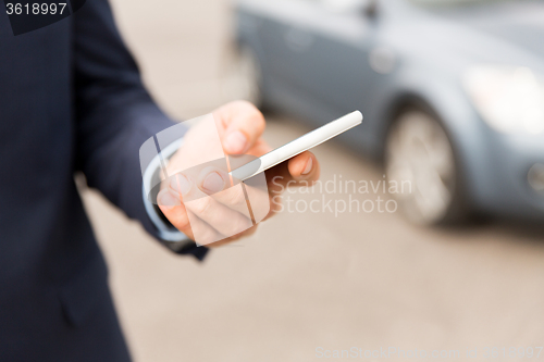 Image of close up of man hand with smartphone and car