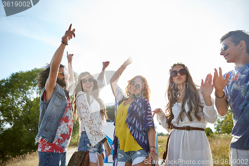 Image of happy young hippie friends dancing outdoors