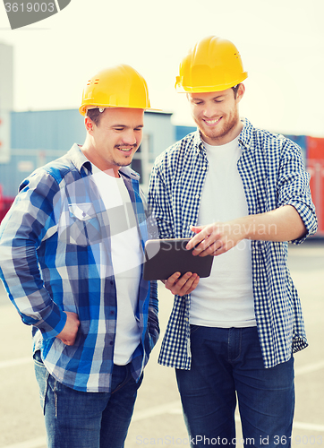 Image of smiling builders in hardhats with tablet pc