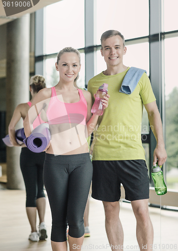 Image of smiling couple with water bottles in gym