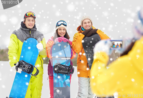 Image of happy friends with snowboards and smartphone