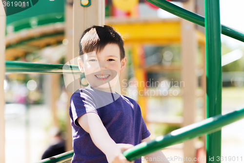 Image of happy little boy climbing on children playground