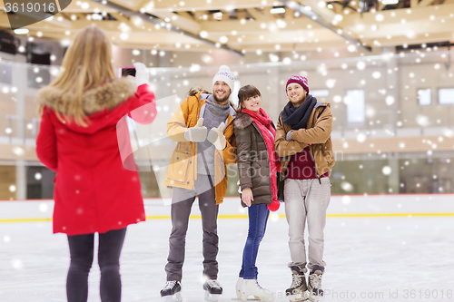 Image of happy friends taking photo on skating rink