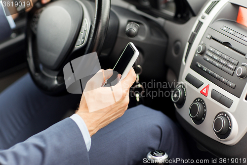 Image of close up of man hand with smartphone driving car