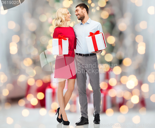 Image of happy couple with gift boxes over christmas lights