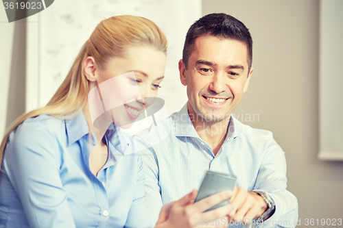 Image of smiling businesspeople with smartphones in office